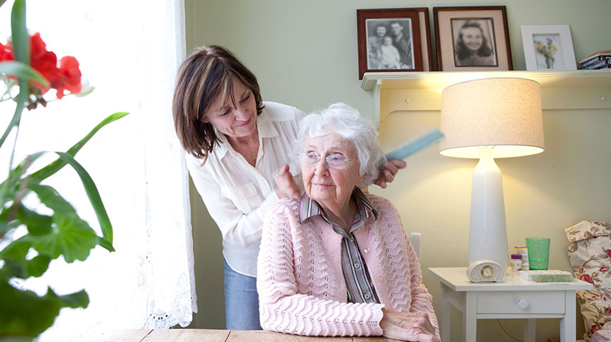 Woman combing hair of elderly woman.