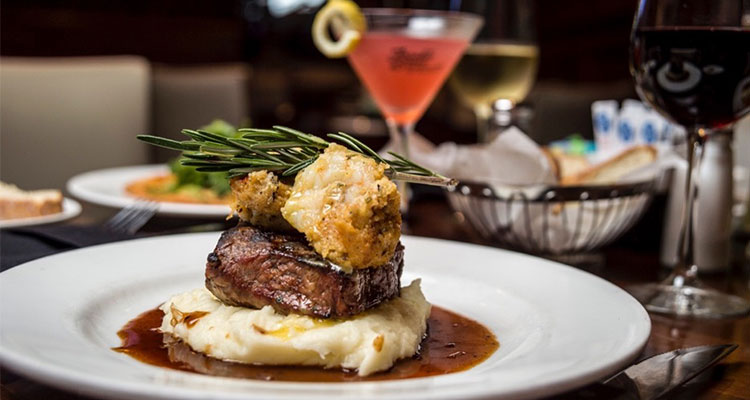 Grilled steak over mashed potatoes and gravy topped with a sprig of rosemary.