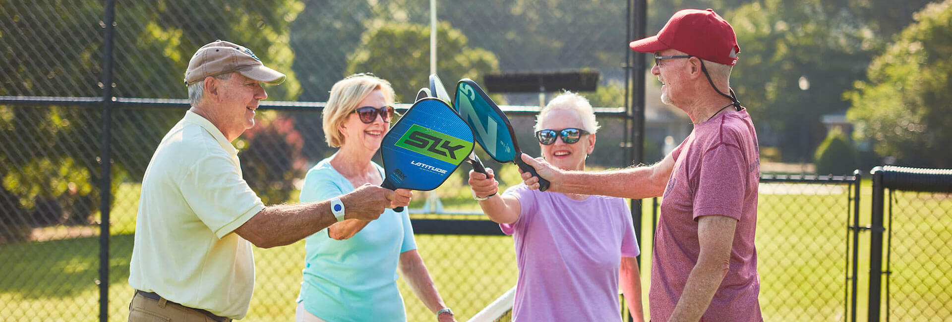 Group of seniors with pickleball rackets meeting at center of court
