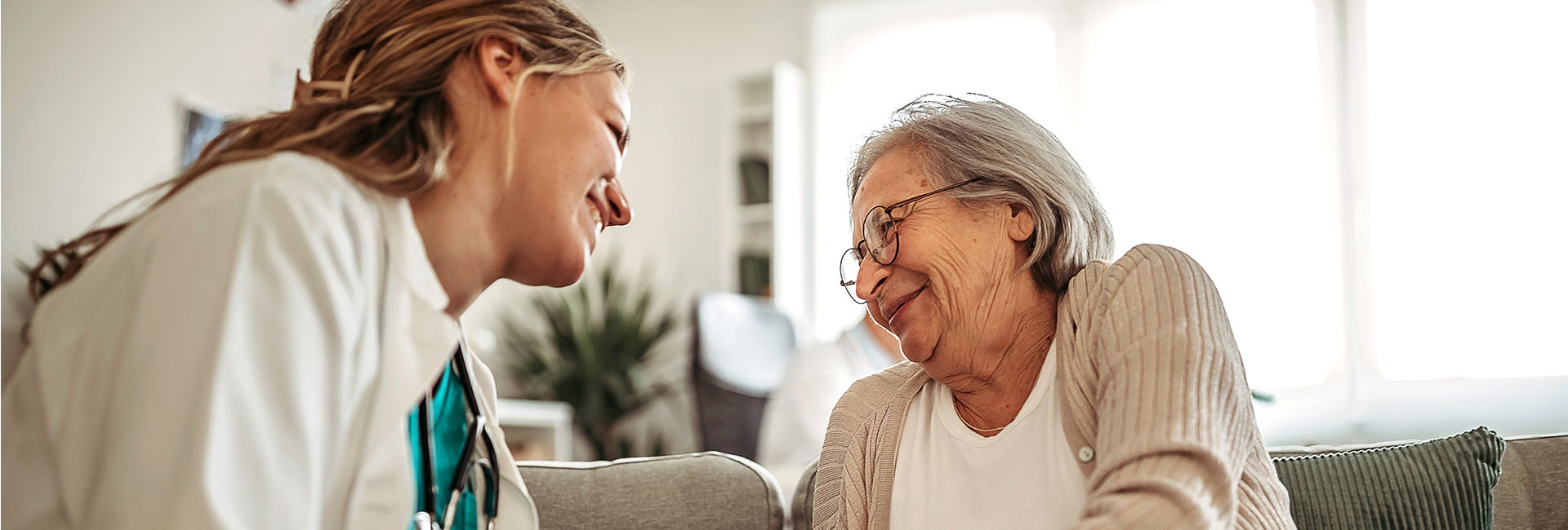 A caring nurse smiling at her older female patient.